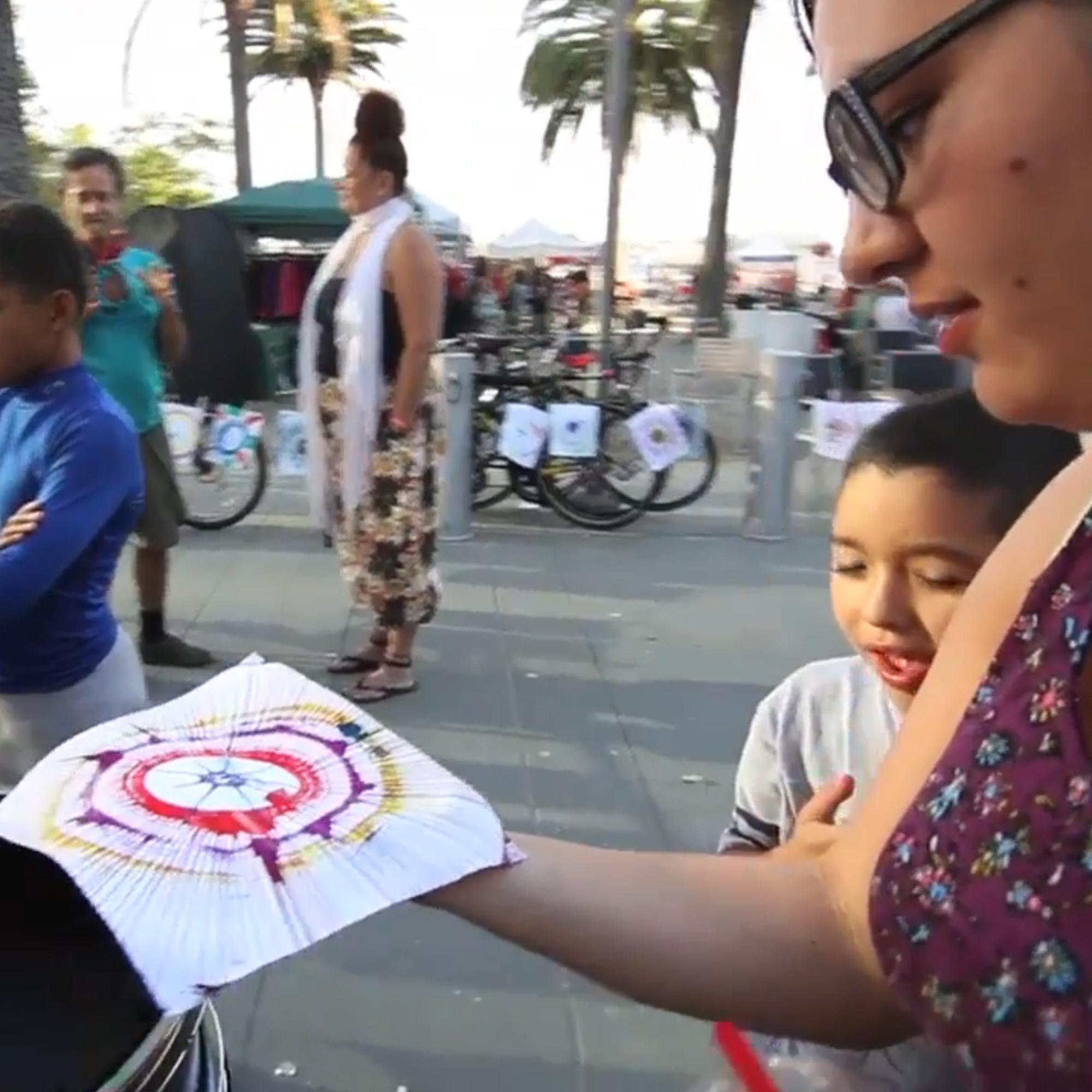 Guest pedaling the Spin Art Bike to create colorful artwork at an event, with vibrant paints splashing onto the spinning canvas.